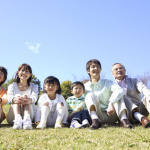 芝生に座る三世代ファミリー